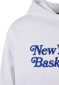 Witte hoodie met een zachte textuur voorzien van blauwe geborduurde tekst die "New Basket" zegt. Inclusief een capuchon met trekkoord en gestikte naden.
