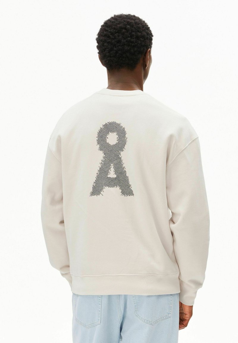 Felpa beige chiaro con un motivo grafico testurizzato in grigio scuro sul retro. Collo a giro e polsini a costine completano il design.