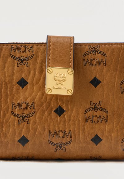 Portefeuille en cuir brun texturé avec des logos MCM noirs et des motifs en diamant, doté d'une sangle en cuir beige avec une plaque MCM München dorée.
