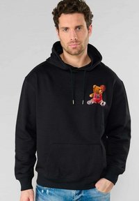 Zwarte hoodie van katoen, met een op de borst geborduurd berenfiguur in basketbaloutfit, voorzien van koordjes en een voorste buideltas.