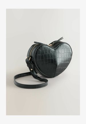 Čierna crossbody taška v tvare srdca vyrobená z umelej krokodílej kože. Má zlatý zips a nastaviteľný popruh. Hladký povrch s embosovaným vzorom.