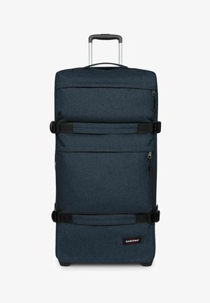 Grande valigia morbida blu scuro con due cinghie di compressione orizzontali, tasche con cerniera, manico telescopico e logo Eastpak vicino al fondo.