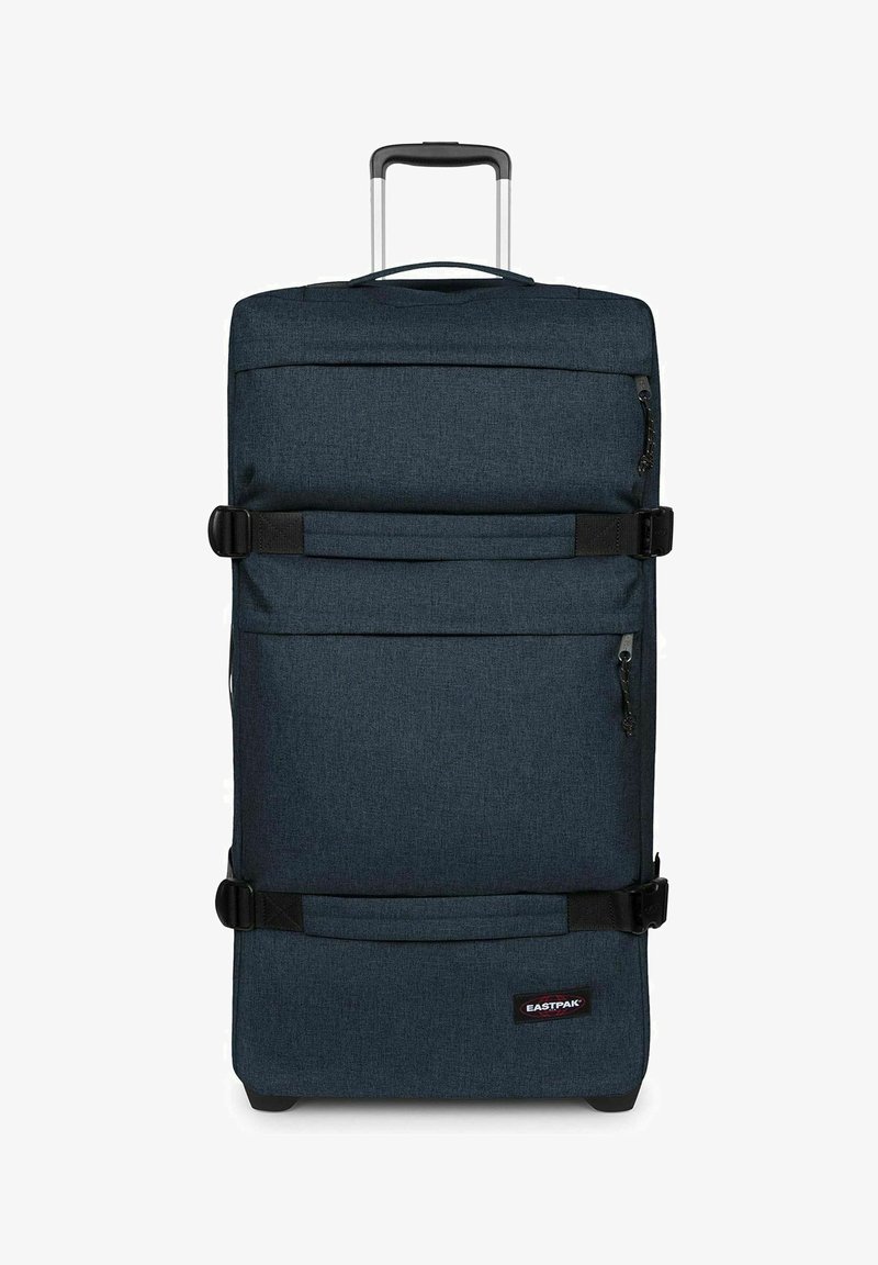 Grande valise souple bleu foncé avec deux sangles de compression horizontales, poches zippées, poignée télescopique et logo Eastpak près du bas.