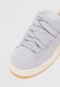 Sneaker in suede viola chiaro con lacci testurizzati, suola in gomma bianca e un piccolo logo sulla linguetta. Presenta un cappuccio della punta liscio.