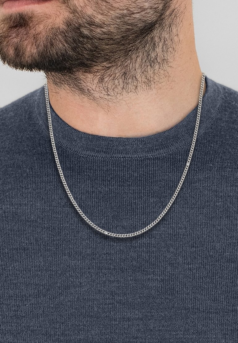 Colier din argint așezat pe un pulover gri închis, având un design răsucit, cu o textură netedă și o grosime medie.