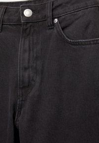 Čierne denimové rifle s klasickým dizajnom päť vreciek, kovovým zapínaním na gombík a jemnou textúrou, s prešívaným detailom pozdĺž švov.