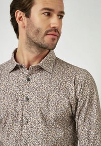 Bruine gestippelde overhemput met een paisley ontwerp, voorzien van een verspreide kraag en zwarte knopen, gemaakt van lichtgewicht stof.