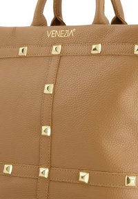 Karmelowa skórzana torba z tłoczeniem w kształcie złotych piramid, z fakturowaną powierzchnią i detalami ściegów. Na górze tłoczone logo "VENEZIA".