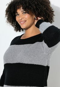 Strickpullover mit schwarzen und grauen horizontalen Streifen. Rundhalsausschnitt, lange Ärmel, strukturierter Stoff und überschnittene Schultern.