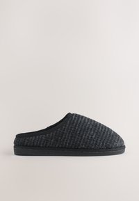 Chausson noir à enfiler avec une tige texturée, une forme arrondie, un tissu doux et une semelle en caoutchouc noir. Pas de marque visible ni d'ornements.