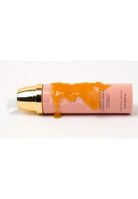 Flacon de sérum rose avec un capuchon doré, buse de distribution blanche, sérum orange dégoulinant sur le côté. Le texte sur le flacon est clair et lisible.