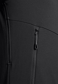 Sezione di abbigliamento sportivo nero con tessuto liscio, cuciture a contrasto e una tasca con zip e un tab di apertura testurizzato.