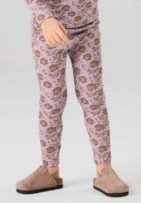 Enfant portant des leggings côtelés roses avec un imprimé floral marron et des sabots marron en daim à semelles noires sur un fond clair.