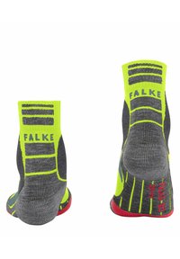 Calze sportive grigie con accenti giallo brillante, dotate di polsini a costine, suola testurizzata e dettagli rossi sul tallone e sulla punta.