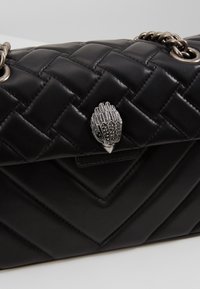 Borsa a tracolla in pelle trapuntata nera con una tracolla in catena argentata e un decorative fermaglio a forma di testa d'uccello in argento sulla pattina.