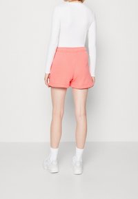 Růžové šortky z bavlněné směsi s elastickým pasem, mají volný střih a ohrnuté nohavice. Kombinované s bílou dlouhým rukávem a bílými teniskami.