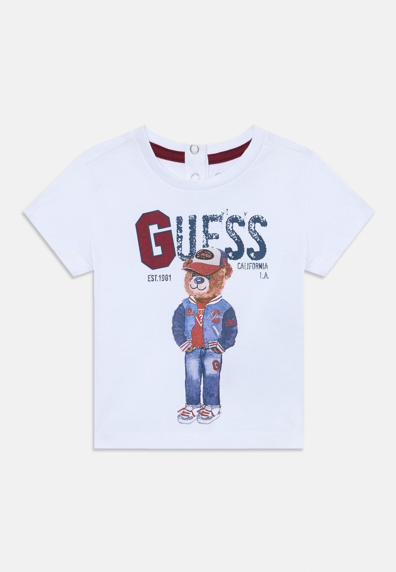 Hvid T-shirt med korte ærmer, der har et grafisk motiv af en bjørn iført en blå jakke og jeans, med teksten "GUESS CALIFORNIA" trykt på forsiden.