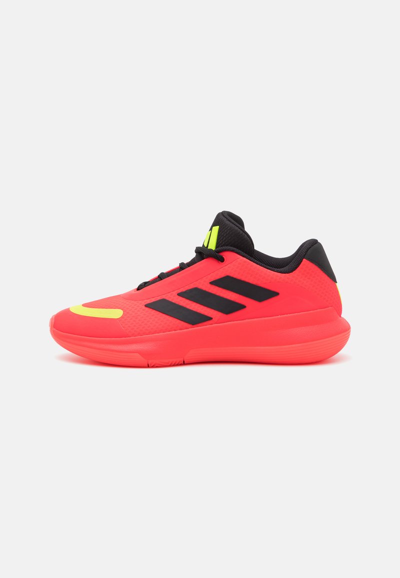 Pantofi sport roșii cu un superior texturat, accente negre și un logo galben strălucitor. Talpa este solidă și groasă pentru susținere.