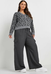 Grijze luipaardprint cardigan met knoopsluiting, gecombineerd met donkergrijze cargo-broek met een losse pasvorm, zijzakken en een elastische taille.