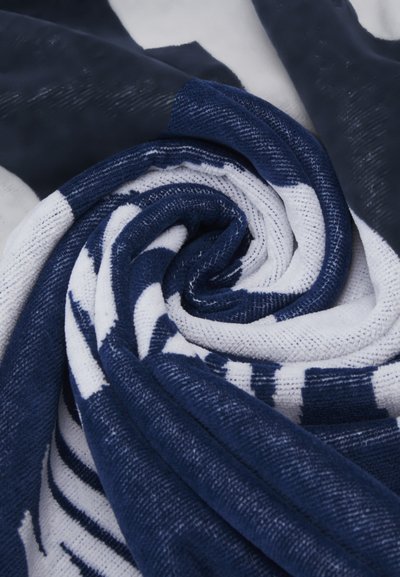 Écharpe rayée bleu marine et blanche, en tissu texturé, présentée dans un motif en spirale. Le matériau présente de subtiles variations de texture et d'épaisseur.