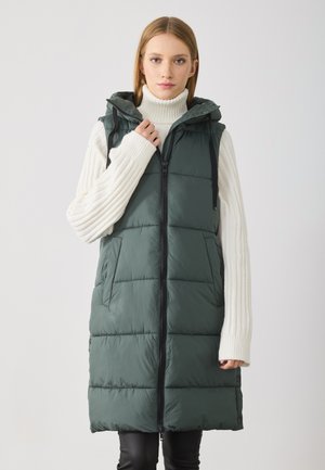 Gilet matelassé sans manches vert foncé avec une fermeture éclair à l'avant, une capuche et des poches latérales. Présente une texture lisse et un design à panneaux cousus.