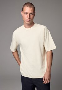 Crewneck short-sleeve t-shirt in light beige cotton fabric, featuring a relaxed fit and visible stitching details.