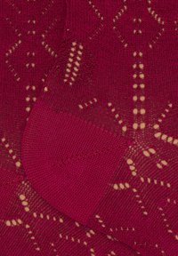 Red knitted fabric features a geometric pattern with cut-out details. Smooth texture with varying thickness, showcasing intricate stitchwork.