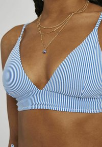 Haut de bikini rayé bleu et blanc avec un design triangulaire, des bretelles ajustables et une bande texturée en bas. Colliers en or superposés visibles.