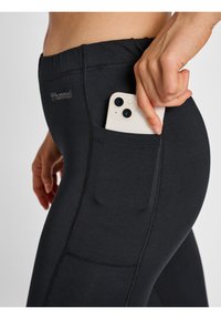 Svarta träningstights i slät tyg, med en säker sidficka för en smartphone och kontrasterande sömmar.