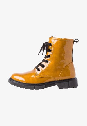Żółte lakierowane botki za kostkę z czarnymi sznurówkami, okrągłym noskiem, fakturowaną powierzchnią i grubą czarną podeszwą. Posiadają siedem oczek na sznurówki oraz pętelkę.