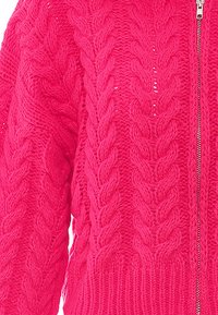 Cardigan lavorato a maglia di un vivace rosa shocking con un motivo a treccia, dotato di una zip a tutta lunghezza e orlo a coste. Texture morbida che offre calore.