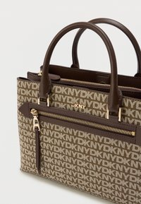 Καφέ τσάντα από ύφασμα με υφαντό μοτίβο λογότυπου, διπλούς χειρολαβές, πάνω φερμουάρ και χρυσές λεπτομέρειες.