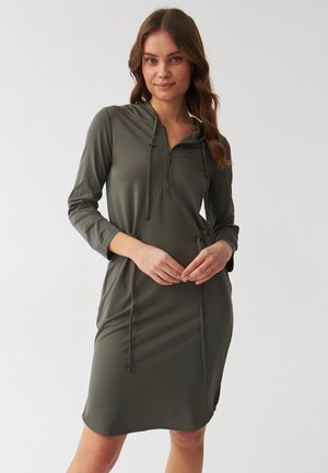 Olive green hooded dress with long sleeves, zip closure, adjustable drawstrings, and side slits for ease of movement. Smooth fabric texture.
