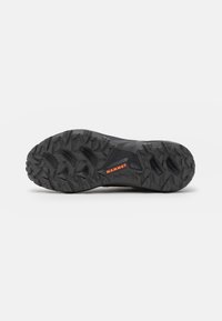 Black trail running shoe sole featuring deep treads, synthetic material, and a bright orange "MAMMUT" logo. Textured for grip.