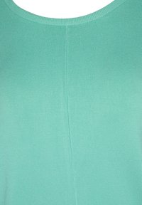 Mátově zelený pletený top s kulatým výstřihem a středovým vertikálním švem procházejícím látkou.