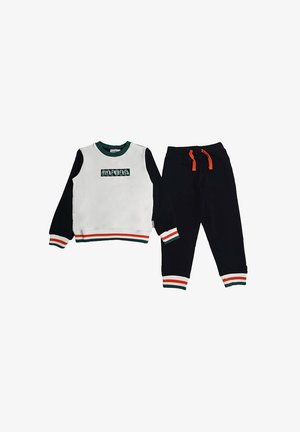 Completo felpa e pantaloni. Parte superiore bianca con maniche nere, scollo verde e dettagli a strisce multicolori. Pantaloni neri con cordino arancione.