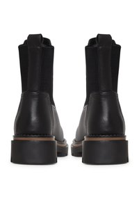 Botas de tobillo de cuero negro con paneles elásticos a los lados, diseño de puntera redonda, suela de goma y un ligero tacón. Detalles de costura a lo largo de los bordes.