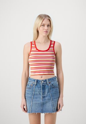 Top court à rayures rouges et jaunes avec un décolleté arrondi et une texture côtelée, associé à une jupe en denim mini taille haute.