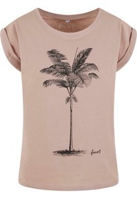 T-shirt rose clair avec des manches retroussées, ornée d'un graphisme de palmier noir et du texte "forest" en bas. Texture de tissu douce.
