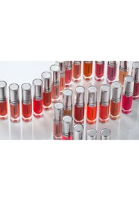 Ventiquattro lucidalabbra in contenitori cilindrici di vetro con tappi argentati. I colori includono tonalità di rosa, rosso, arancione e nude.