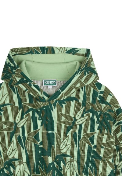 Sweat à capuche vert et beige, doté d'un tissu texturé avec un motif de feuilles de bambou, des poignets côtelés et une capuche à large col.