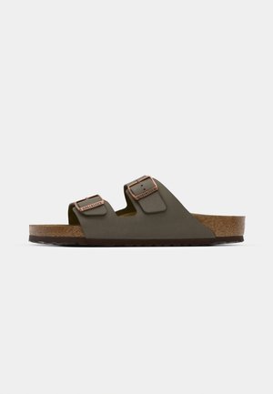 Dunkelgrüne Slipper-Sandalen mit zwei verstellbaren Riemen und kupferfarbenen Beschlägen, ausgestattet mit einem Korkfußbett und einer strukturierten Gummisohle.