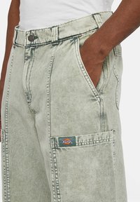 Světle zelené džíny cargo s vysokým pasem, velkými předními kapsami a malým logem Dickies na boku. Texturovaná tkanina se zašlým vzhledem.