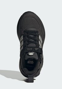 Chaussure de sport noire avec un dessus texturé, des panneaux en mailles, des rayures argentées et une large sangle avec le logo Star Wars sur la languette.