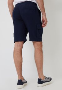 Shorts cargo marine avec une taille élastique, comprenant des poches latérales et une poche arrière. Le tissu a une texture lisse et légère. Design décontracté.