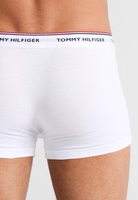 Boxeri din bumbac alb cu un design ajustat. Prezintă un tiv cu marcă, cu dungi navale, roșii și albe. Textură netedă.