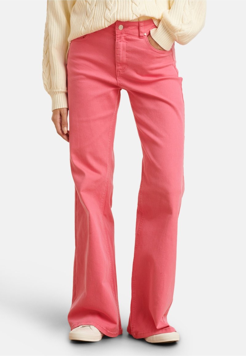 Pink flared jeans made from cotton, featuring a classic five-pocket design, standard waistband with a button, and a smooth texture.