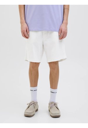 Shorts di cotone bianchi con una vestibilità rilassata, caratterizzati da un taglio dritto e tasche laterali. Indossati con scarpe grigio chiaro e calze bianche.
