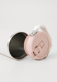 White stainless steel travel mug with a pink plastic lid, featuring a flip-top opening and a silver metal accent. Interior is dark.