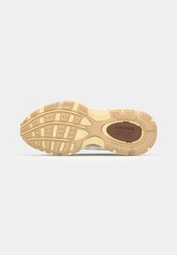 Semelle de sneaker Lacoste, en caoutchouc texturé beige avec un motif de traction, mettant en avant un logo marron au centre et un sculptage détaillé pour le soutien.